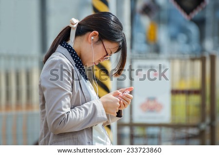 KYOTO, JAPAN - OCTOBER 21: : Woman with a smartphone in Kyoto, Japan on October 21, 2014. Unidentified Japanese female uses her device while waits for a train on a plateform