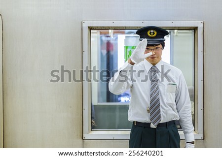 KYOTO, JAPAN - OCTOBER 23:  Train Conductor in Kyoto, Japan on October 23, 2014. Unidentified Japanese train conductor observes passenger before giving a sign to move the train