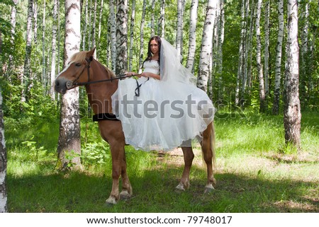 a young woman sits astride a horse in a wedding dress