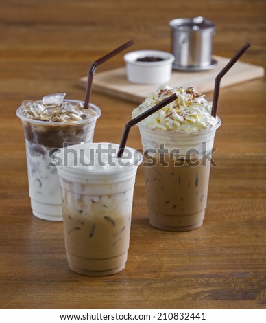 Ice coffee with whipped cream and coffee beans on wooden table.