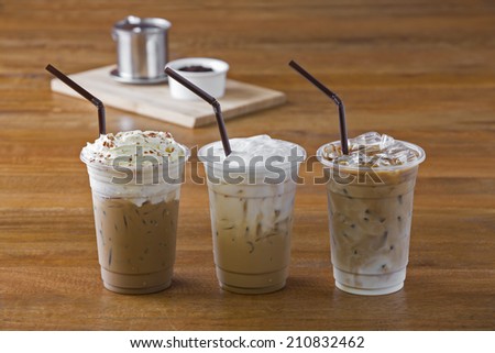 Ice coffee with whipped cream and coffee beans on wooden table.