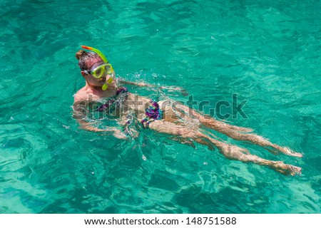 Girl swimming in the clear water of the sea with a mask and snorkel