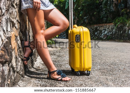 Girl with a yellow suitcase on a resort in Thailand