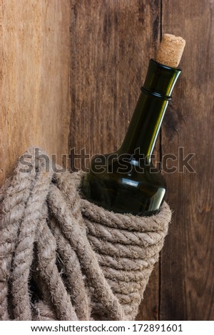 bottle of wine wrapped with rope on the background of the old wooden planks