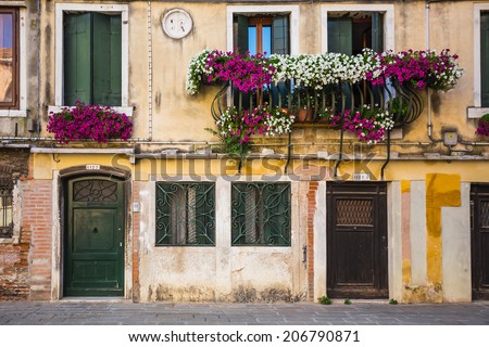 ITALY - JUNE 26, 2014: Windows and doors in an old house decorated with flower pots and flowers