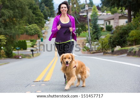 A pretty woman jogging with her golden retriever dog