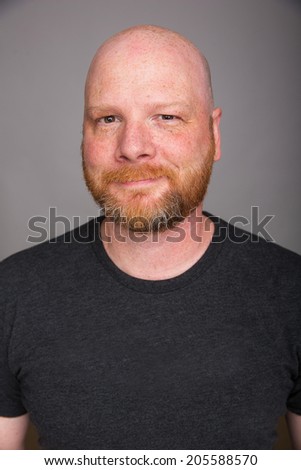 A friendly looking bald man with a red beard