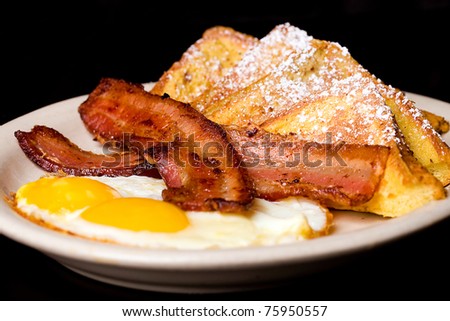 A plate with French Toast, Bacon and Eggs for breakfast.