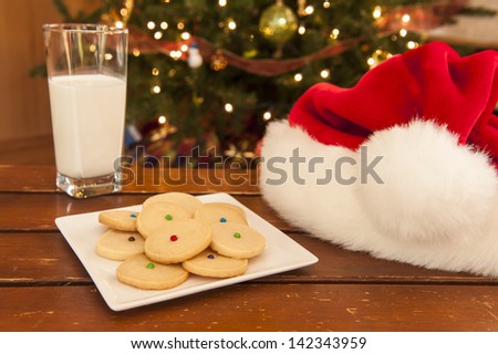 Plate of shortbread cookies with a glass of milk and Santa hat