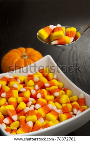 Spoon scooping candy corns out of a square dish