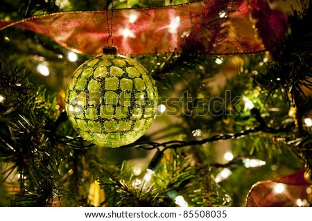 Christmas tree light sparkle illuminating a multi faceted green Christmas ball