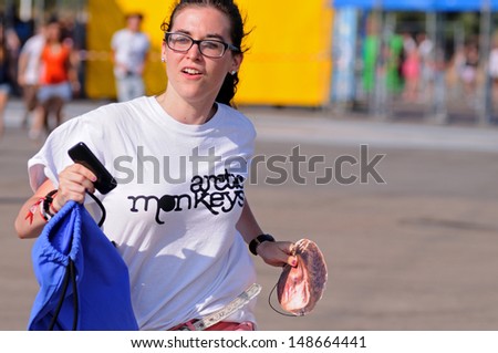 BENICASIM, SPAIN - JULY 19: A girl with an Arctic Monkeys band shirt, runs to catch the first row at FIB (Festival Internacional de Benicassim) 2013 Festival on July 19, 2013 in Benicasim, Spain.
