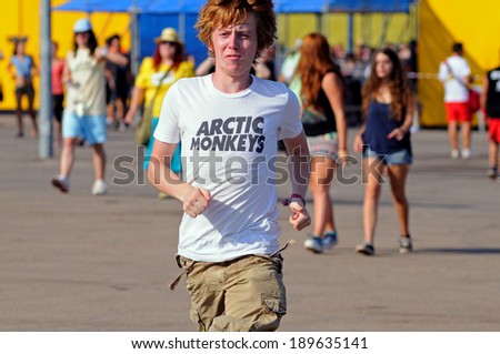 BENICASIM, SPAIN - JULY 19: A redhead boy with an Arctic Monkeys band shirt, runs to catch the first row at FIB 2013 Festival on July 19, 2013 in Benicasim, Spain.