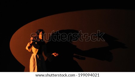 BARCELONA - JAN 13: An actress and her silhouette, with a knife in the hand, plays in the comedy Shakespeare For Executives on January 13, 2013 in Barcelona, Spain.