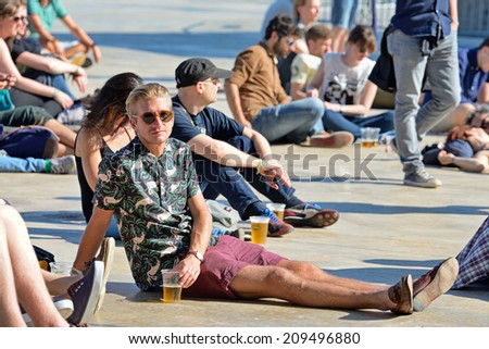 BARCELONA - MAY 30: A man from the audience watches a concert and have a beer sitting in the floor at Heineken Primavera Sound 2014 Festival (PS14) on May 30, 2014 in Barcelona, Spain.