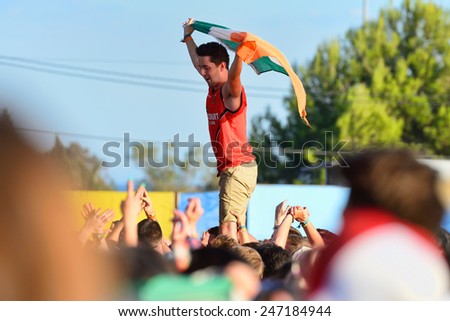 BENICASSIM, SPAIN - JULY 20: Young man from the crowd cheering, with an Irish flag, at FIB Festival on July 20, 2014 in Benicassim, Spain.