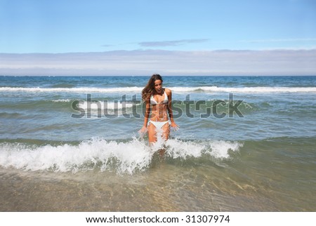 beautiful girl in bikini being splashed by cold wave
