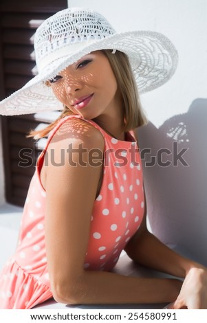Young beautiful woman in hat with shadows on the face posing in white house
