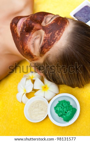 Beautiful happy woman in spa making face mask treatment