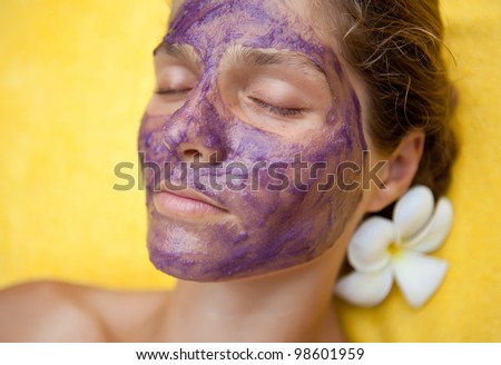 Beautiful happy woman in tropical spa making face mask treatment