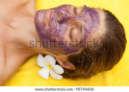 Young beautiful woman in tropical spa making face mask treatment