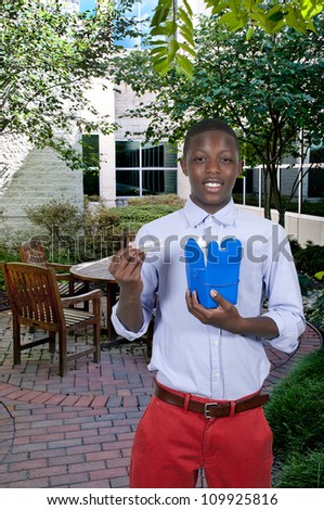 Handsome teenage black African American man eating Chinese Japanese or Asian takeout food