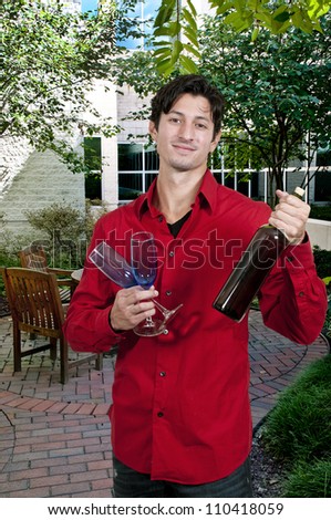 Handsome young man holding a wine glass and wine bottle