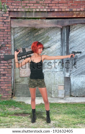Beautiful young woman holding an automatic assault rifle and pistol