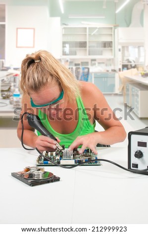 Beautiful woman repairing a printed circuit board with a forced air soldering iron