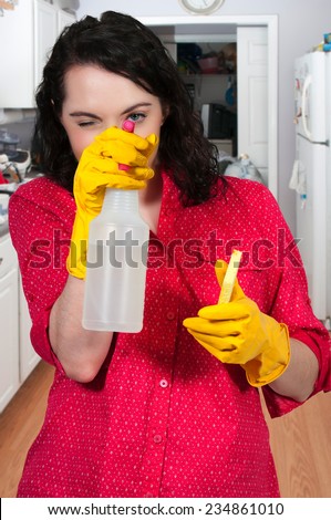 Glove wearing beautiful woman or maid cleaning house with a sponge and spray bottle with cleaner