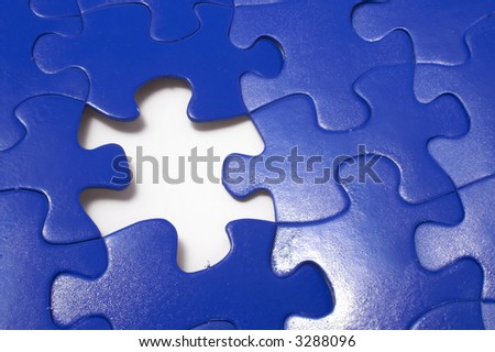A close-up of a jigsaw puzzle with a missing puzzle piece.
