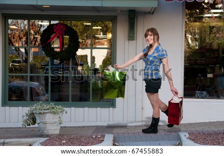 A beautiful young woman on a shopping spree in front the stores of a strip mall