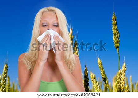 A beautiful woman with a cold, hay fever or allergies blowing her nose
