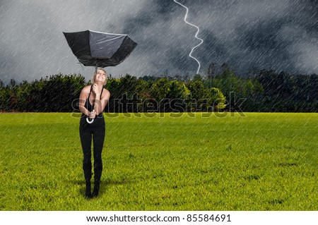 A beautiful young woman holding a broken umbrella in the rain