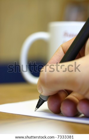 Pen in man\'s hand writing on paper in office