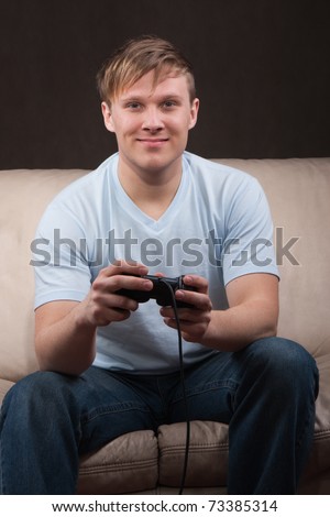 Young man playing video games on gray background