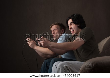 two friends pushing each other while playing video games on gray background