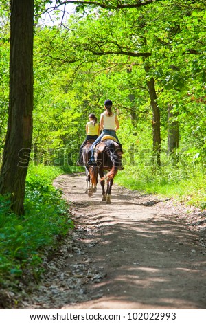 Two a young girls on horseback riding in the route