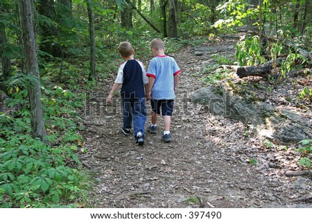 Two five year old boys walking along wooded trail.