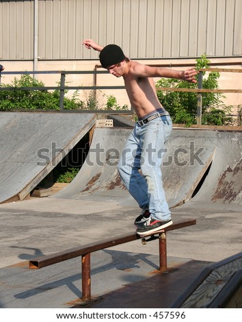 Male teen skateboarder sliding on rail at skate park.
