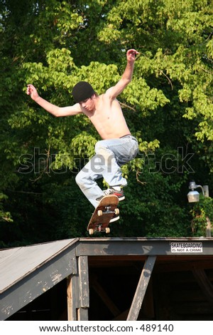 Male teen skateboarder jumping off a platform at a skate park.