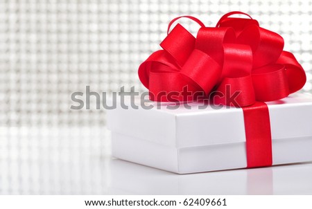 white gift with the red ribbon on white background with reflection