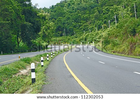 Asphalt road sharp curve along with tropical forest zigzag ahead.