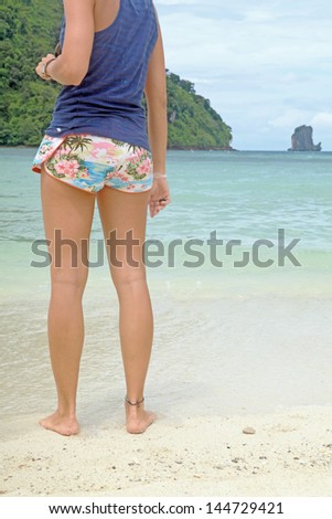 Young Woman with good figure legs stand back on the beach of Thailand southern sea island