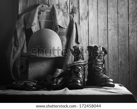 Still life art photography on vintage army jacket field coach helmet jungle boots and metal bullets box in black and white version