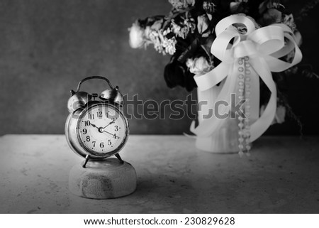 Vintage gold alarm clock with time concept over dried flowers black and white version