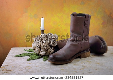 Brown genuine haft boots on grunge with dry flowers and candles still life art photography