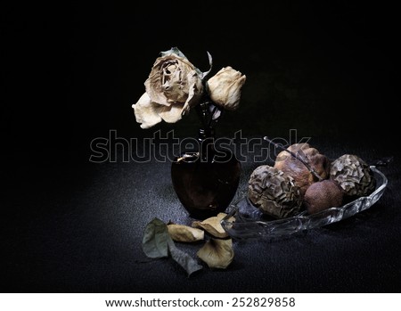 Dried roses in heart shape bottle and rotten fruits light painting still life art