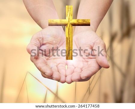 Human hands praying over the golden cross and amazing light background
