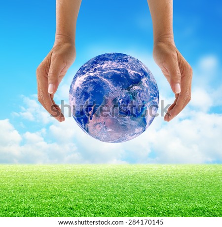 Human hands protect global Earth over gas clouds and Sun over green glass a World Environment Day Concept Elements of this image furnished by NASA